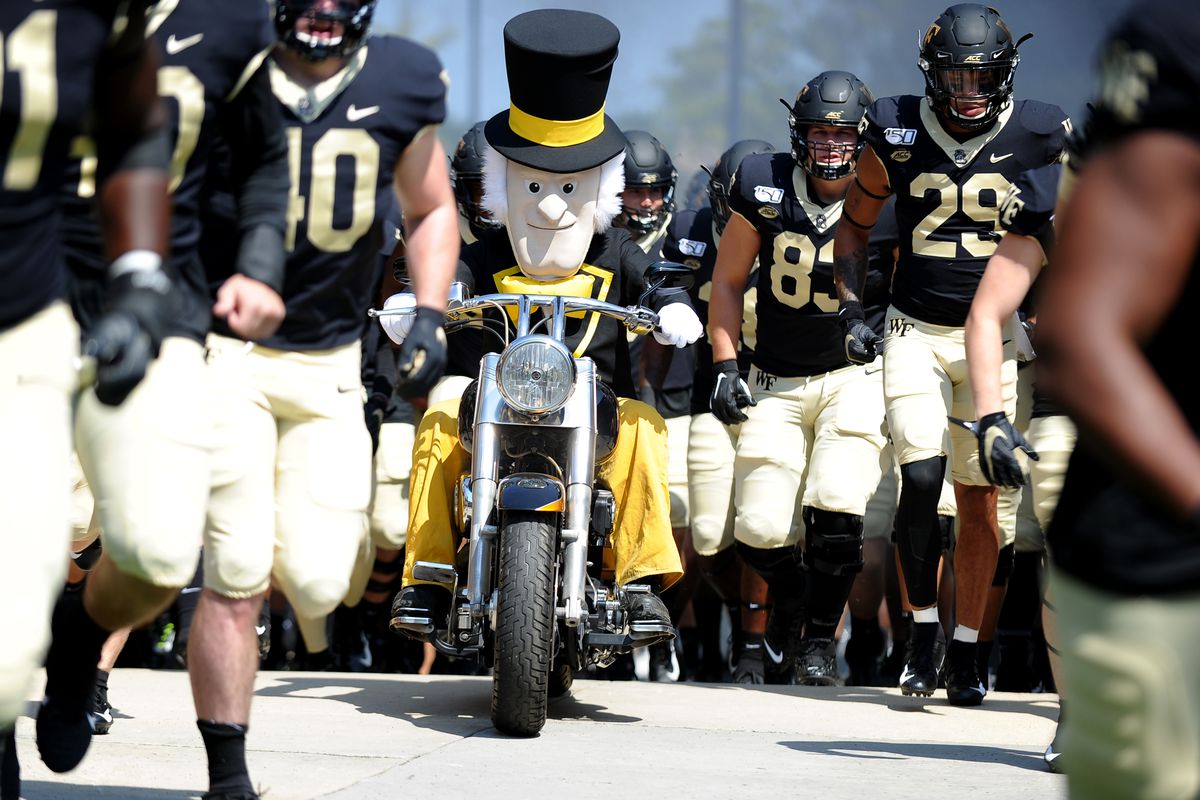 Wake Forest mascot riding a motorcycle amidst football team taking the field